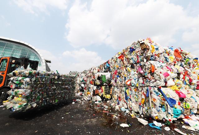 仁市的一处废品回收中心,工作人员正在处理大批的压缩塑料等生活垃圾